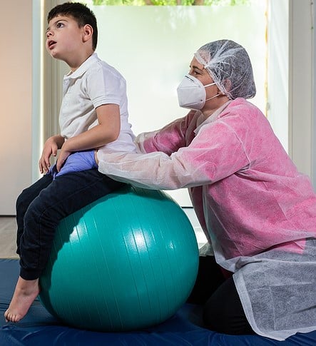 A Disabled Child Is On Top Of A Large Green Ball Doing Physical - Keren ...